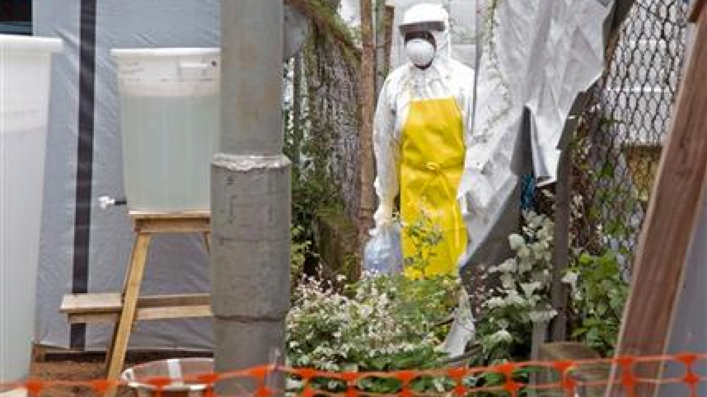 This Aug. 12, 2014 file photo shows a healthcare worker walking near a Ebola isolation unit wearing protective gear against the virus at Kenema Government Hospital in Kenema, Sierra Leone. Federal researchers next week will start testing humans with an experimental vaccine to prevent the deadly Ebola virus. The National Institutes of Health (NIH) announced Thursday that it is launching the safety trial on a vaccine developed by the agency’s National Institute of Allergy and Infectious Diseases and GlaxoSmithKline. They will test 20 healthy adult volunteers to see if the virus is safe and triggers an adequate response in their immune systems. (AP Photo/ Michael Duff, File)