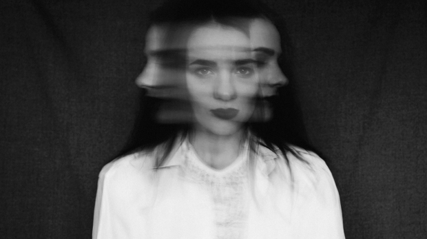 crazy portrait of a girl with mental disorders and split personality. Black and white in vintage style with added grain and motion blur