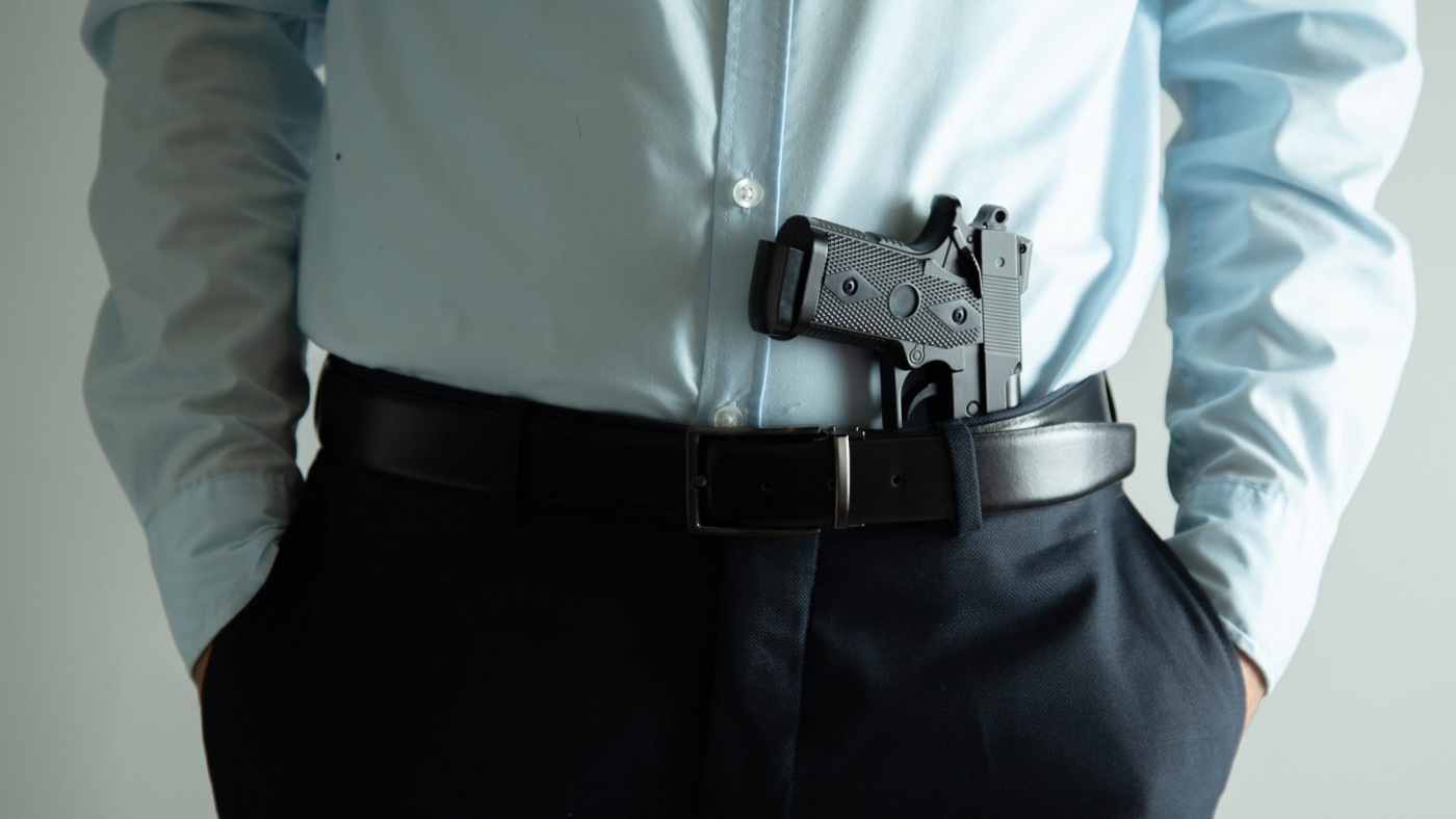 man hand holding gun on grey background
