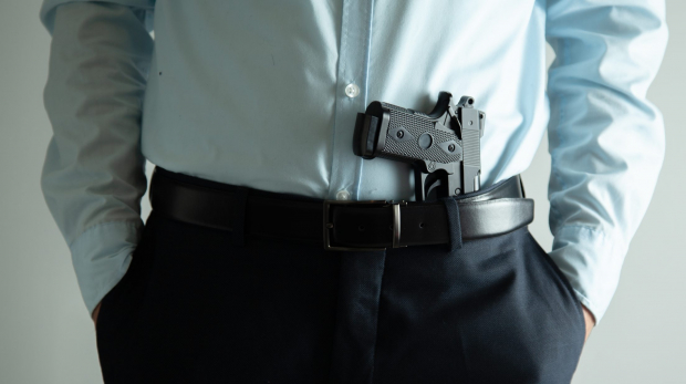 man hand holding gun on grey background