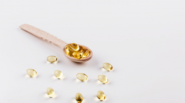 Oil capsule for hair with vitamin E lie on wooden spoon