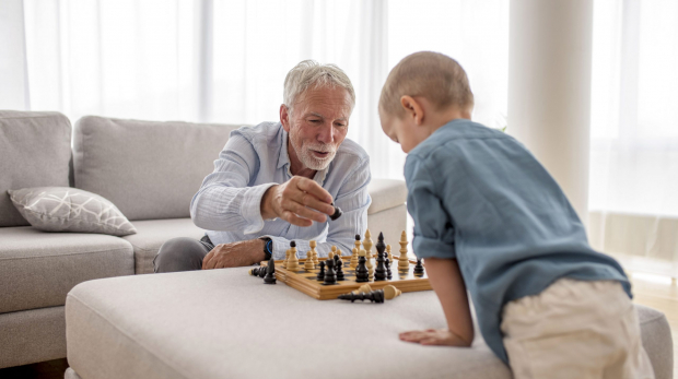 The adorable little boy playing chess with his grandfather
