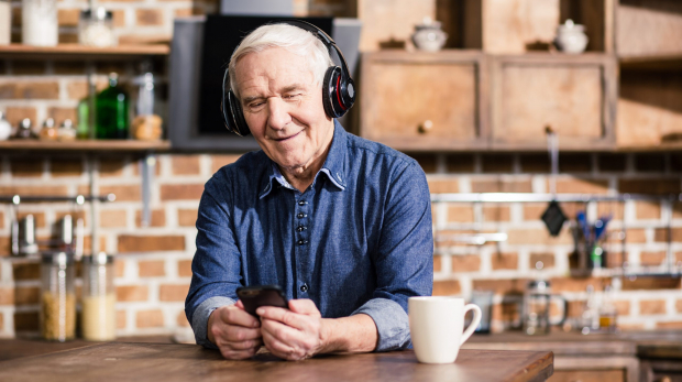 Switch it on. Pleasant smiling elderly man using his smartphone while listening to music