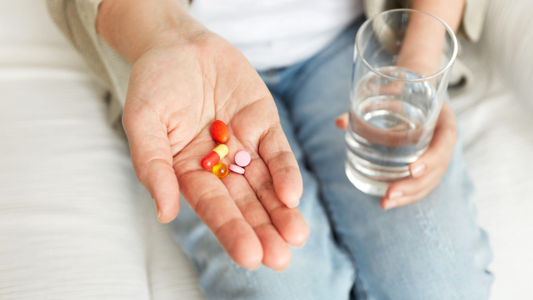 Pills, tablets, vitamins and drugs heap in mature hands, closeup view.
