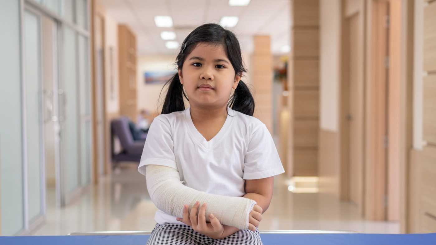 Asian girl treatment in hospital lying on the bed hurting with broken arm back from surgery.