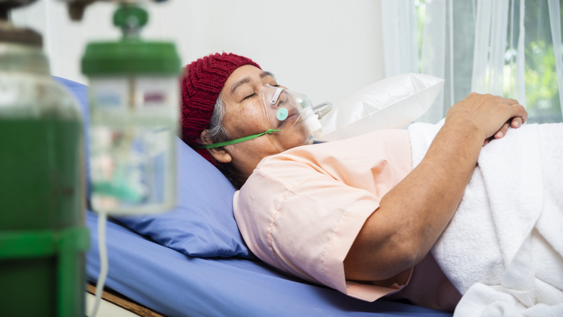 Asian elderly woman wearing wool hat with oxygen mask to breathing while  lying on patient bed, senior female medical and healthcare concept