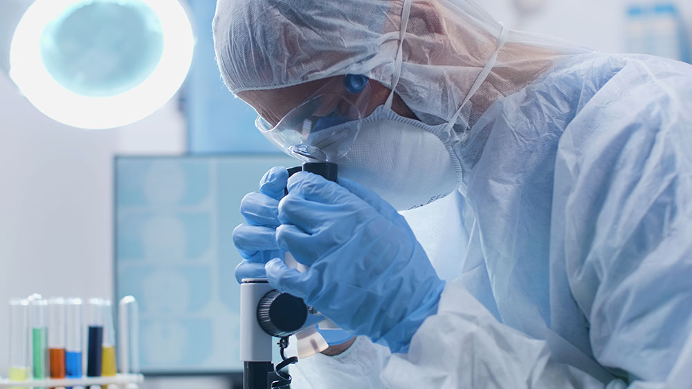 Biochemist Looks Thru Microscope During Clinical Trial Session