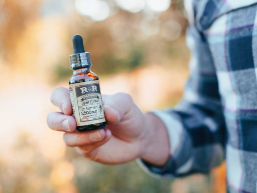 CBD Man Holds Bottle Photo