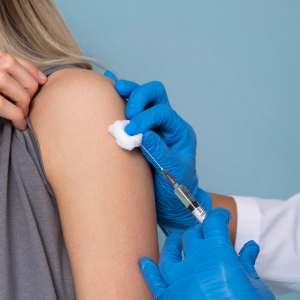 Woman getting vaccinated by a doctor wearing blue gloves, representing infectious-disease-clinical-trials research.