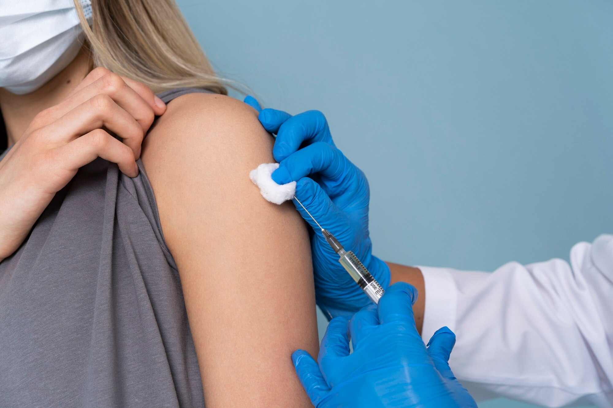 Mujer vacunada por un médico con guantes azules, en representación de la investigación de ensayos clínicos de enfermedades infecciosas.
