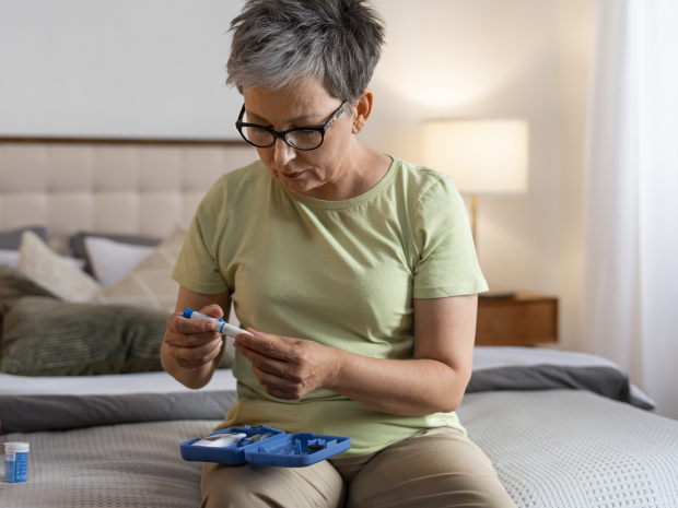 Woman checking blood sugar levels at home as part of monitoring for metabolic or lipid disorders like hypertriglyceridemia.